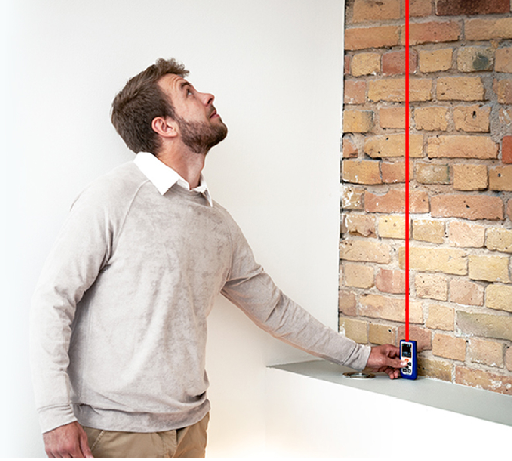 EAGLINE digital measuring tool in use beside a brick wall